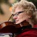 Violin instructor Ewa Bujak played in protest in front of Derham Hall opposing cuts to the music and theater programs Thursday.