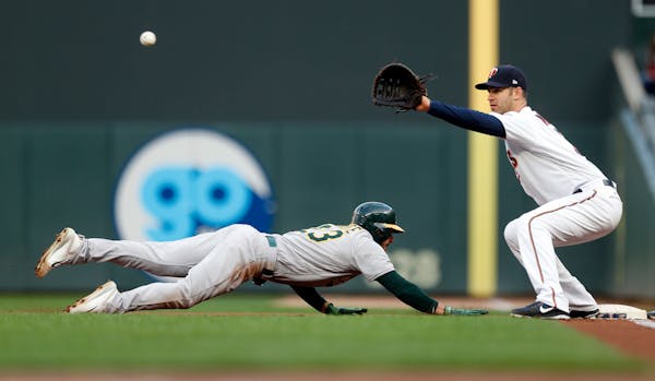 Oakland Athletics' Matt Joyce dives safely back to first to beat the pickoff throw to Minnesota Twins first baseman Joe Mauer