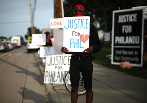 Demonstrators, including Emmanuel Kandolo, foreground held signs as they took part in the vigil along a busy Larpenteur Ave. ] JEFF WHEELER ï jeff.wh