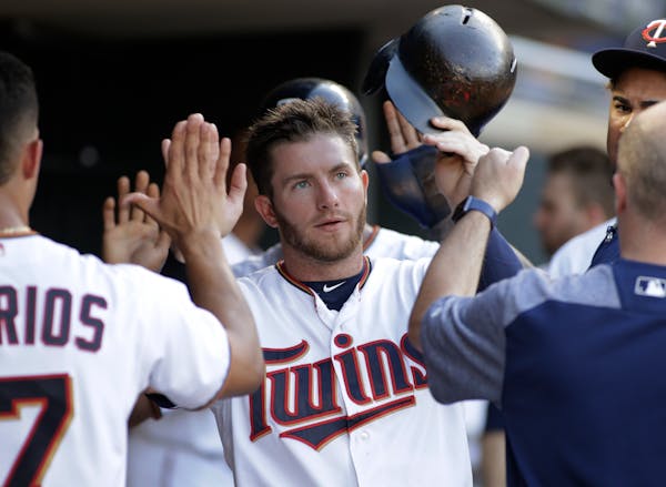 Minnesota Twins' Robbie Grossman is congratulated by teammates after he scored during the third inning of the team's baseball game against the Baltimo