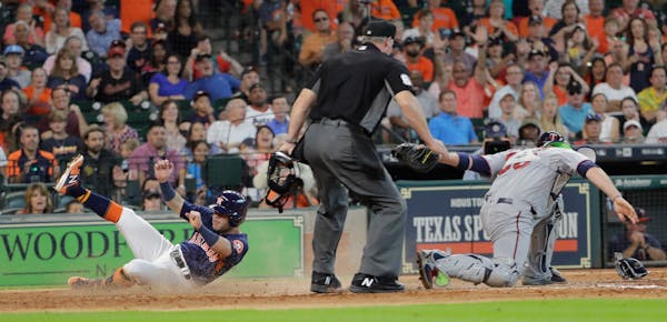 The Astros' Jose Altuve slid safely across home plate to score as Twins catcher Chris Gimenez reached to tag him during the seventh inning Sunday.