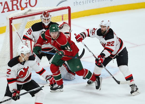 Minnesota Wild center Mikael Granlund (64) is shoved by New Jersey Devils defenseman Kyle Quincey (22) as he screens goalie Cory Schneider just as an 