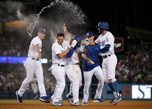 The Los Angeles Dodgers celebrate a walk-off single by Justin Turner, center, after a baseball game against the Minnesota Twins in Los Angeles, Wednes