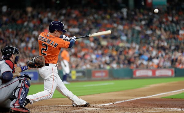 Houston Astros' Alex Bregman hits an RBI double to score Yuli Gurriel as Minnesota Twins catcher Jason Castro watches during the second inning of a ba