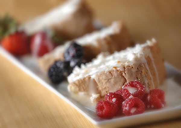 Angel food cake gets a finishing touch from an orange powder glaze and fresh berries.