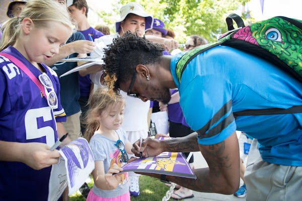 Rodney Adams autographed a pennant for Tylar Amberg, 4, as he arrived at Vikings training camp at Mankato.