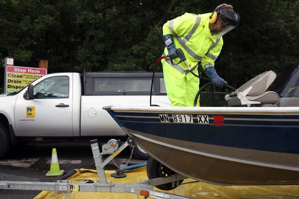 Matt Dwelly, a watercraft inspector with the Minnesota Department of Natural Resources, used hot water to rid a boat of zebra mussels and other invasive species at White Bear Lake.
