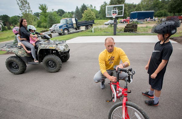 P.J. Fleck worked on his son's Carter's bike as Heather gave the girls a ride on the ATV.