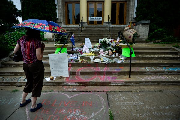 A woman viewed the memorial on the steps of the Lake Harriet Spiritual Community church in south Minneapolis Wednesday as rain began to fall.