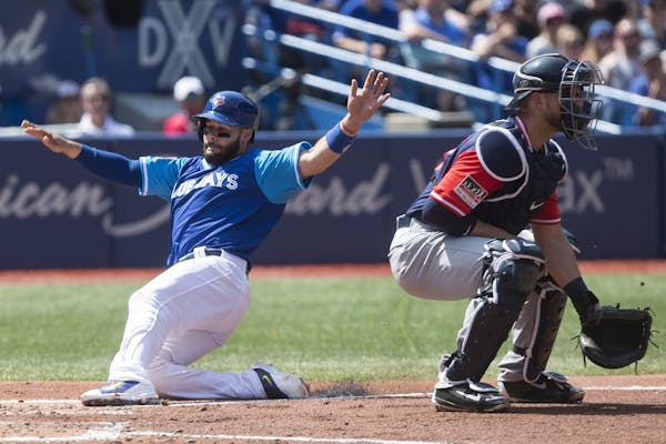 Toronto’s Raffy Lopez, left, scored on a sacrifice fly in front of the Twins’ Mitch Garver, whose first game as a major league catcher was a rough