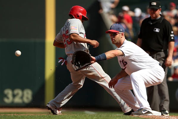 Los Angeles Angels left fielder Ben Revere (25) raced back to first as Minnesota Twins first baseman Joe Mauer (7) checked him with a throw from the m