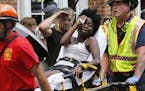 Rescue personnel help an injured woman after a car ran into a large group of protesters after a white nationalist rally in Charlottesville, Va., Satur