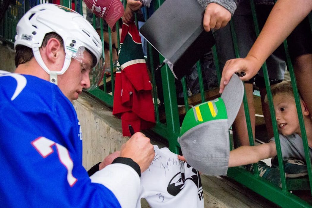 The Wild's Mike Reilly signs autographs after a game.