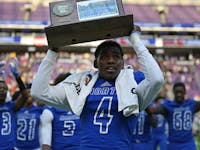 Phaizon Scott brought the Minneapolis North championship trophy to the crowd after the Polars defeated Rushford-Peterson 30-14. ] Shari L. Gross / sgr