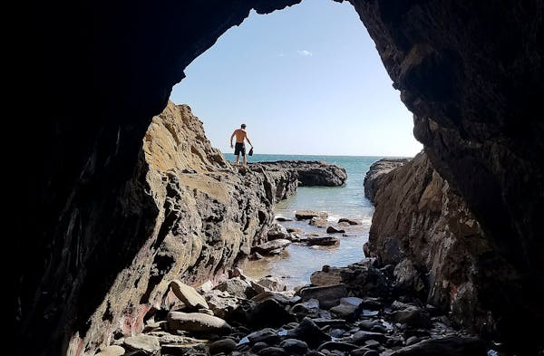 A member of a yoga retreat explores a deep tidal channel that connects the Pacific Ocean to a cave at Playa Maderas, Nicaragua.