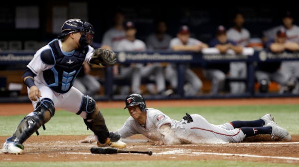 Minnesota Twins' Ehire Adrianza slides home safely ahead of the tag by Tampa Bay Rays catcher Jesus Sucre on a two-run single by Eduardo Escobar durin