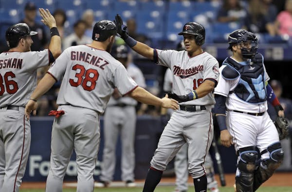 Minnesota Twins' Ehire Adrianza, second from right, celebrates with Robbie Grossman, left, and Chris Gimenez, second from left, after Adrianza hit a t