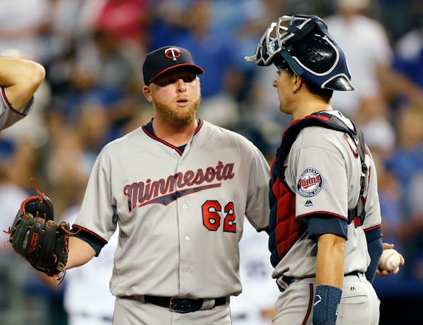 Minnesota Twins relief pitcher Buddy Boshers (62) talks with catcher Jason Castro following a single by Kansas City Royals' Eric Hosmer that scored th