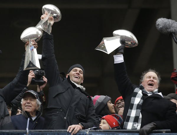 New England Patriots quarterback Tom Brady holds up Super Bowl trophies along with head coach Bill Belichick, right, and team owner Robert Kraft, left
