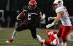 Eden Prairie High School running back D.J. Johnson (5) reached out to block Lakeville North High School defensive back Braden Walsh (16) as he ran tow