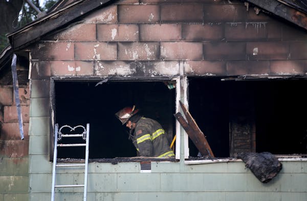 A Minneapolis firefighter looks over the scene of a duplex fire that gutted the upstairs and left two seriously burned Thursday, Sept. 28, 2017, in Mi