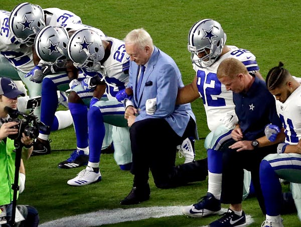 The Dallas Cowboys, led by owner Jerry Jones, center, take a knee prior to the national anthem prior to an NFL football game against the Arizona Cardi