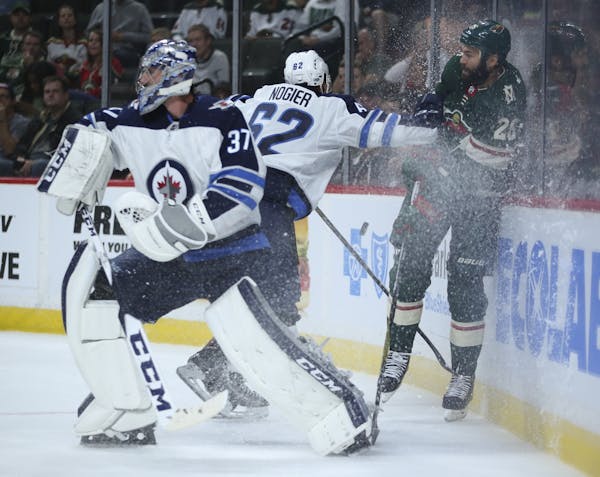 Minnesota Wild right wing Daniel Winnik (26) was checked into the boards by Winnipeg Jets defenseman Nelson Nogier (62) while trying to get to the puc