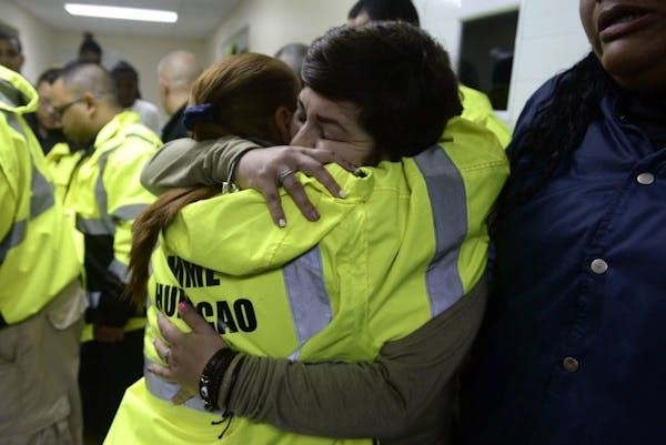 Rescue team members Candida Lozada, left, and Stephanie Rivera, right, hug as they share their frustration over being unable to go out to answer sever