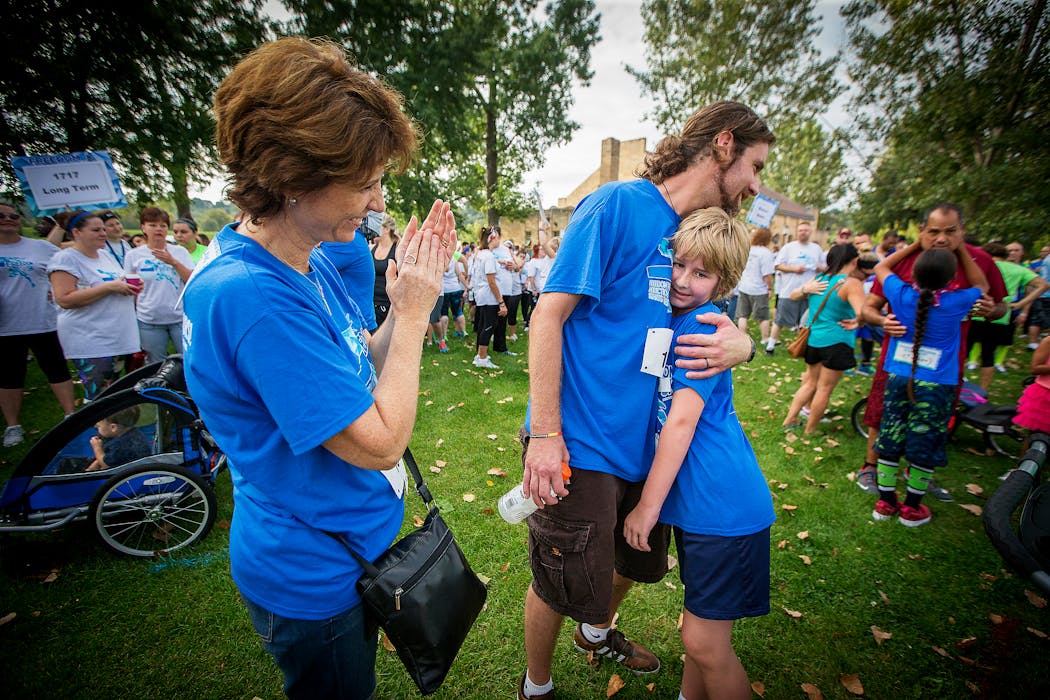 Owen gets a hug from his dad and a nod from his dad's aunt Julie Holtze at the Freedom 5K Run/Walk in St. Paul.
