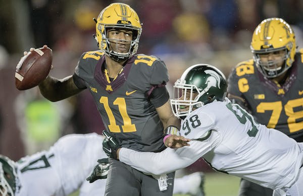 Minnesota's quarterback Demry Croft managed to complete a pass despite defensive pressure by Michigan State's defensive end Demetrius Cooper during th