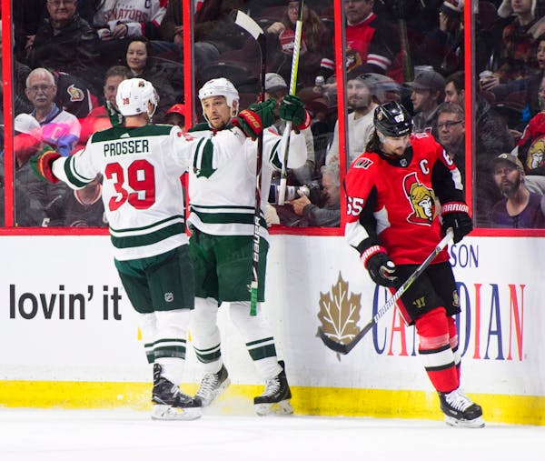 Minnesota Wild's Chris Stewart, center, and Nate Prosser celebrate a goal as Ottawa Senators' Erik Karlsson skates past during second period NHL hocke