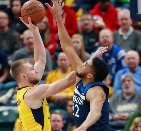 Indiana Pacers forward Domantas Sabonis, left, shoots the basketball defended by Minnesota Timberwolves center Karl-Anthony Towns in the first half of