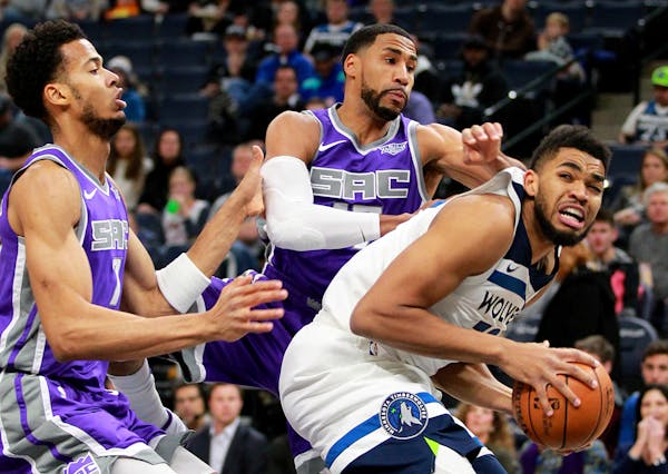 Timberwolves forward Karl-Anthony Towns, right, looks to shoot against Sacramento Kings guard Garrett Temple (17) and forward Skal Labissiere (7)