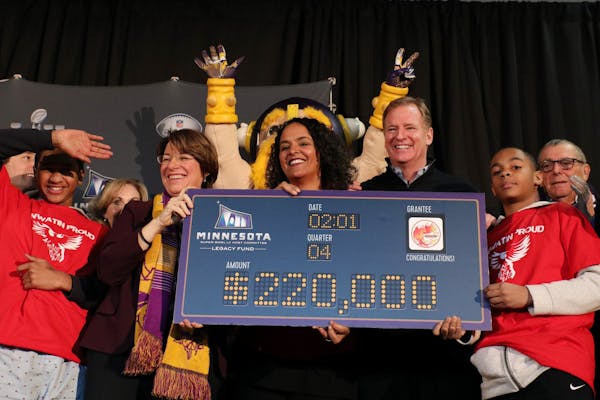 Sen. Amy Klobuchar, Anwatin Middle School principal Ellen Shulman and NFL Commissioner Roger Goodell held ceremonial check for $220 thousand awarded a