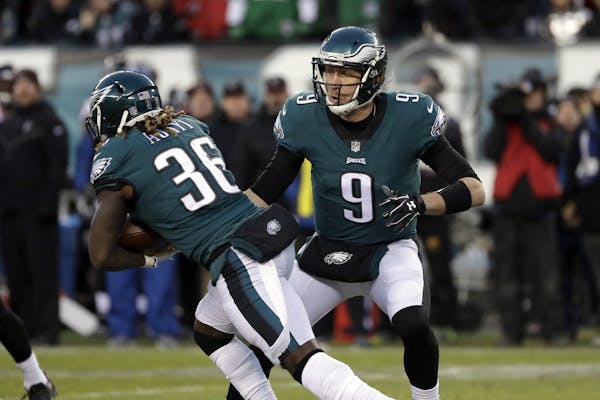 Philadelphia Eagles' Nick Foles, right, hands off to Jay Ajayi during the first half of an NFL divisional playoff football game against the Atlanta Fa