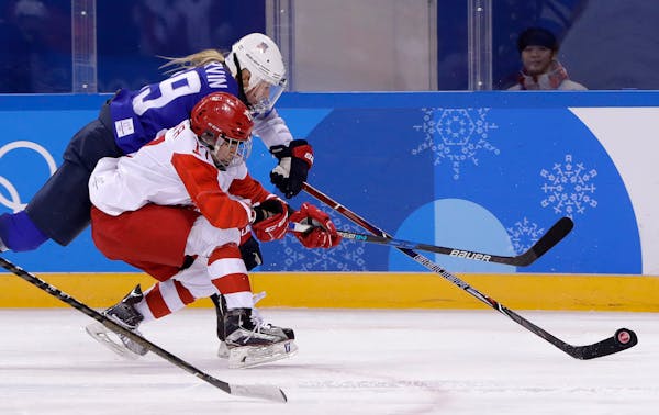 Gigi Marvin (19), of the United States, and Russian athlete Fanuza Kadirova (17) battle for the puck during the third period of the preliminary round 
