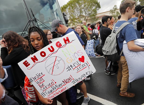 Tyra Hemans, 19, left, and Logan Locke, 17, right, students who survived the shooting at Stoneman Douglas High School, wait to board buses in Parkland