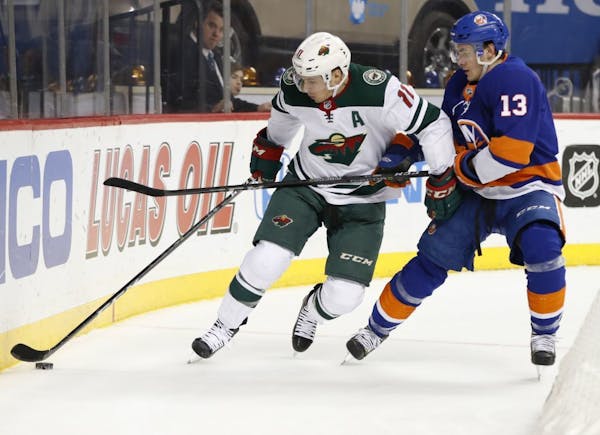 New York Islanders center Mathew Barzal (13) and Minnesota Wild left wing Zach Parise (11) battle for a puck in the first period of an NHL hockey game