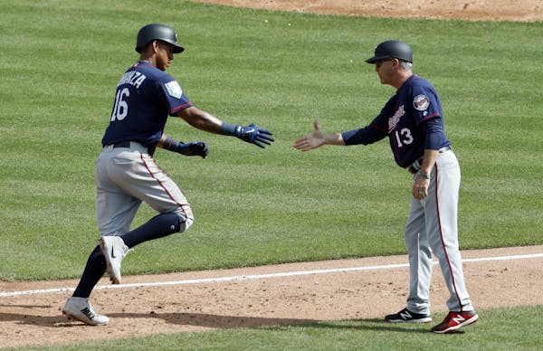 Minnesota Twins’ Ehire Adrianza (16) is congratulated by third base coach Gene Glynn (13) after hitting a two-run home run during the fifth inning o