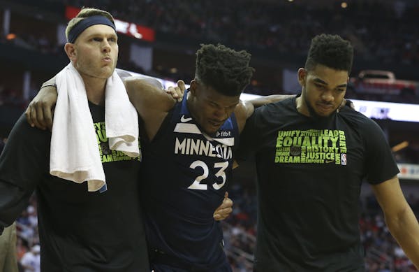 Timberwolves guard Jimmy Butler (23) needed help to get off the floor Friday in Houston.