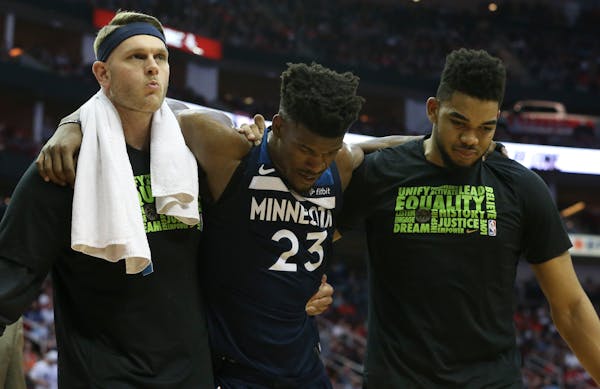 Timberwolves guard Jimmy Butler is carried off the court by teammates after appearing in pain with his knee during the third quarter of Friday's game.
