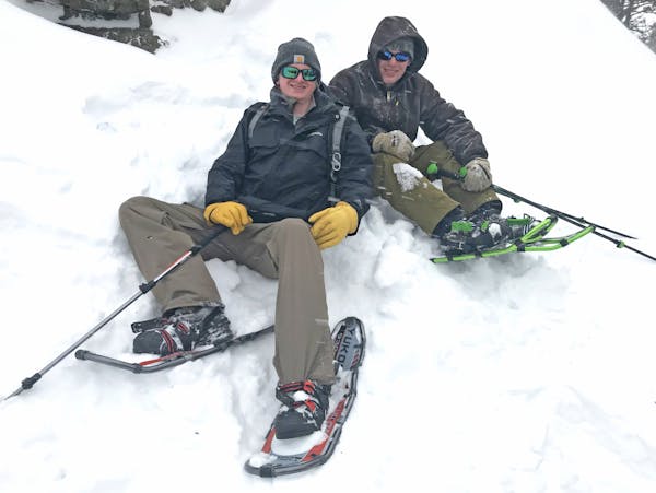 Cole Anderson, left, and Max Kelley relaxed in snow after hiking on snowshoes to a rocky peak in the Bridger Mountains of Montana.
