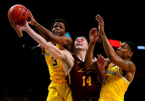 Loyola-Chicago guard Ben Richardson (14) fights for a rebound with Michigan guard Zavier Simpson, left, and Charles Matthews, right, during the second