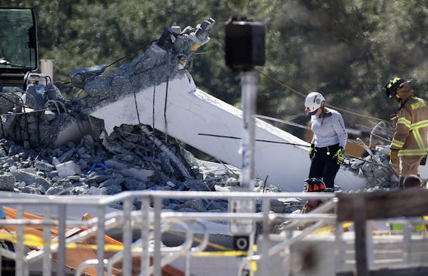 Rescue workers walk on the rubble after a brand-new pedestrian bridge collapsed at Florida International University in Miami on Thursday, March 15, 20
