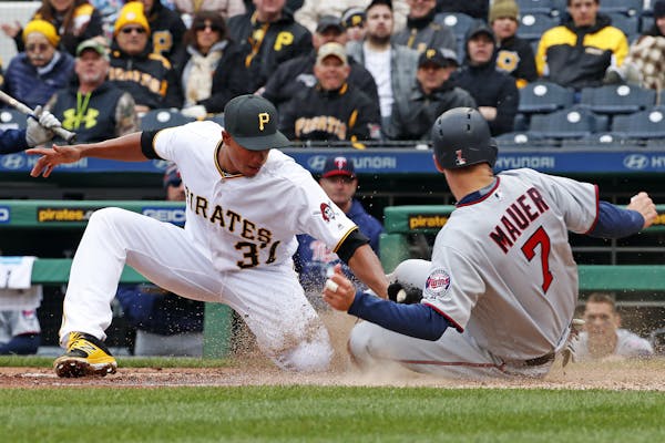 Joe Mauer of the Twins beat Pirates pitcher Edgar Santana’s tag to score on a wild pitch Monday.