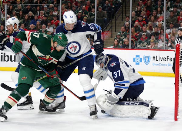 Minnesota Wild left wing Marcus Foligno (17) is stopped by Winnipeg Jets goalie Connor Hellebuyck (37) with defensive help from Jets' defenseman Tyler