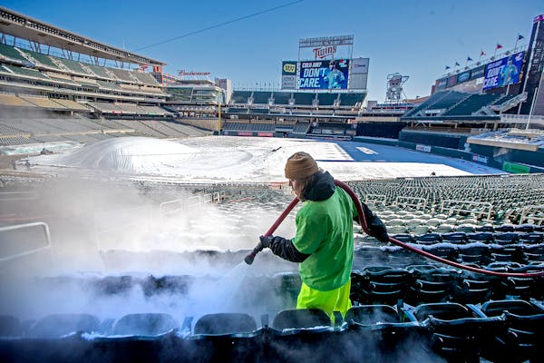 In advance of Thursday's home opener Andrew Hagl, of Columbia Heights, melts snow with hot water on Target Field seats. Twins staff used many strategi