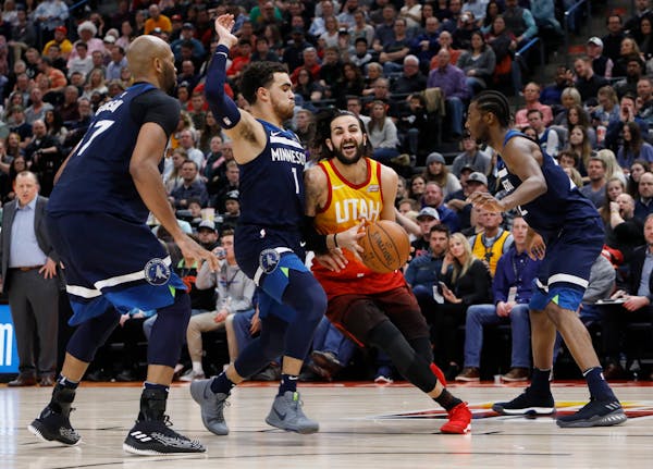 Utah Jazz's Ricky Rubio, middle, drives the basket as Minnesota Timberwolves' Tyus Jones (1) defends during the second half of an NBA basketball game 