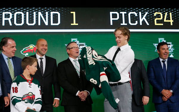Filip Johansson, of Sweden, puts on a jersey after being selected by the Minnesota Wild during the NHL draft in Dallas