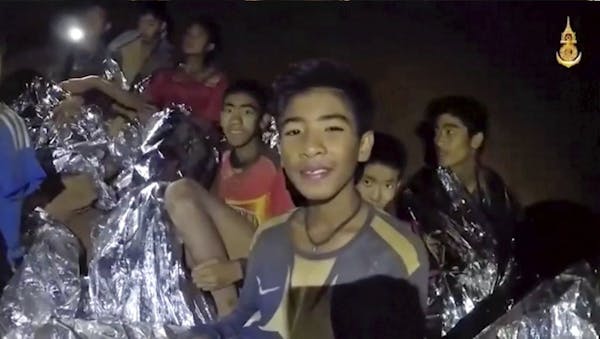 FILE - In this July 3, 2018, file image taken from video provided by the Royal Thai Navy Facebook Page, the boys smile as a Thai Navy SEAL medic helps